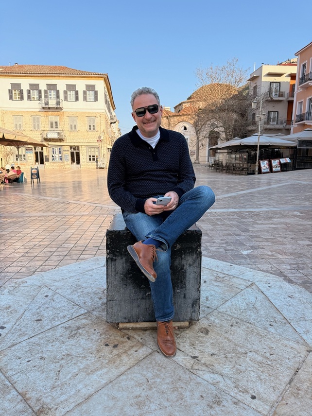 Dmitry Braverman seated outdoors in a sunlit European square